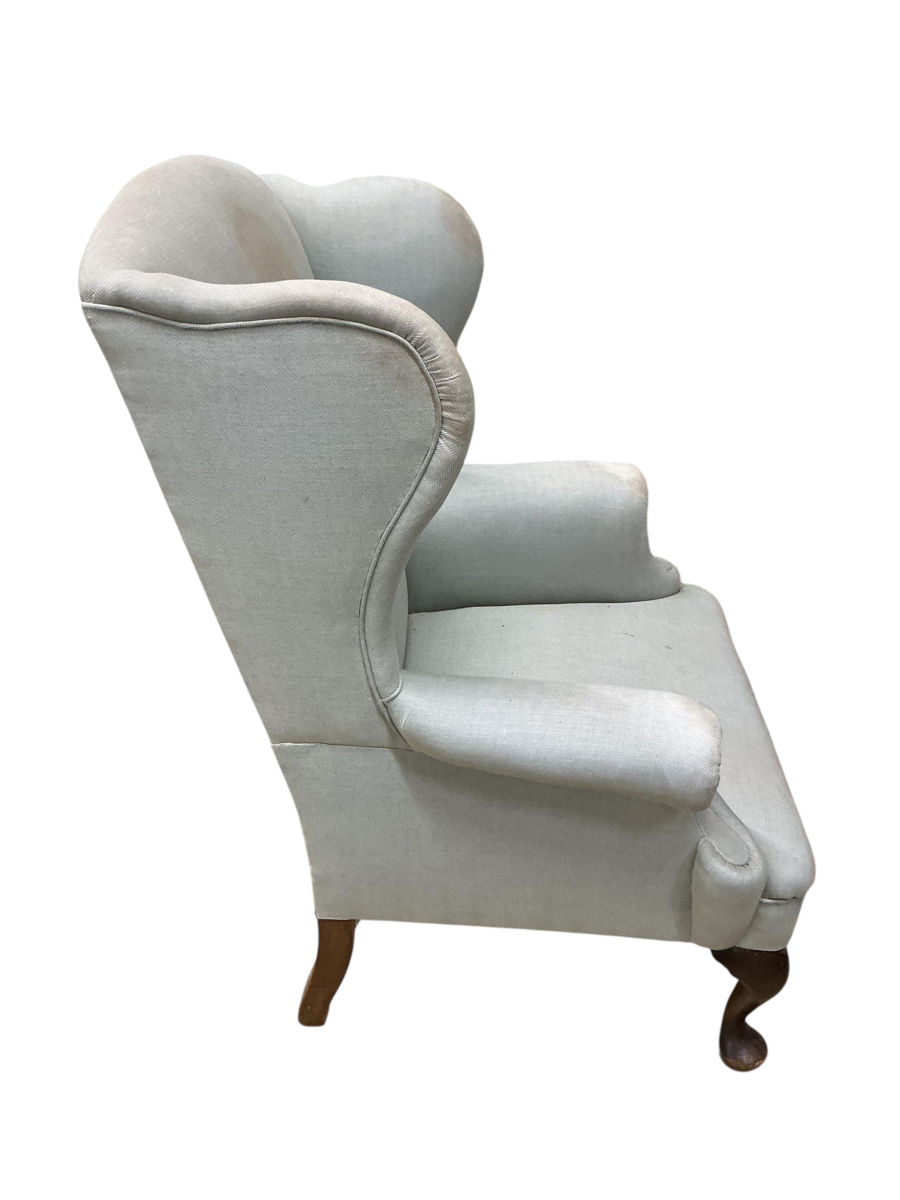 An early 20th century upholstered wing armchair, width 82cm, depth 66cm, height 108cm